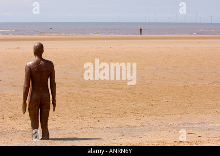 Un altro luogo dove si trova la statua dell'uomo di ferro Antony Gormley sulla spiaggia di Crosby con il parco eolico offshore Burbo Bank in lontananza. Merseyside, Regno Unito Foto Stock