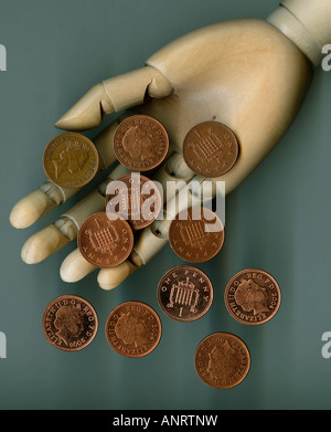 Un penny monete cadere dalla mano di legno, close-up Foto Stock