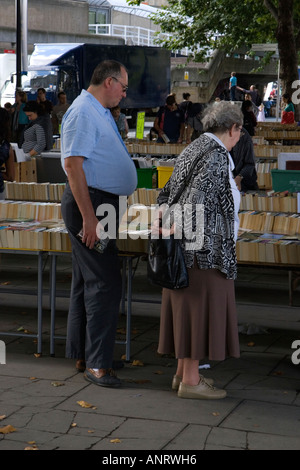 Una donna anziana e un uomo di mezza età di sfogliare libri di seconda mano per la vendita sulla riva sud del fiume Tamigi Foto Stock