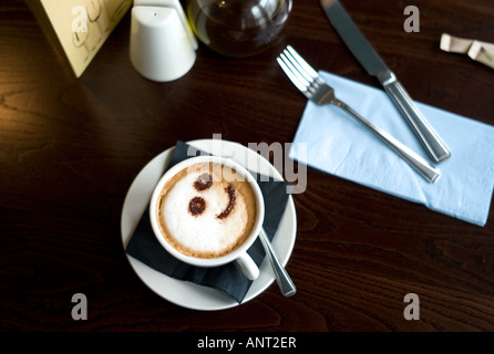 Faccina sorridente nel cioccolato in polvere in una tazza di caffè cappuccino in un cafe bar bistro Foto Stock