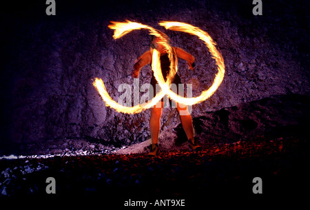 Una performance di artista dimostrando la giocoleria con il fuoco poi o fire fa roteare su Sussex spiaggia di notte. Foto Stock