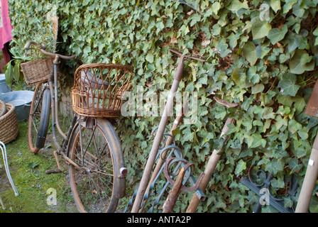 BicycleMBF1729 haute vienne Limousin Francia francese antico bike appoggiato edera parete rivestita con vecchi attrezzi da giardino Foto Stock