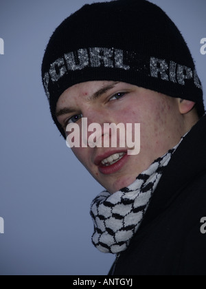 Ragazzo adolescente vestita di nero e di bianco sciarpa a scacchi e un cappellino Foto Stock