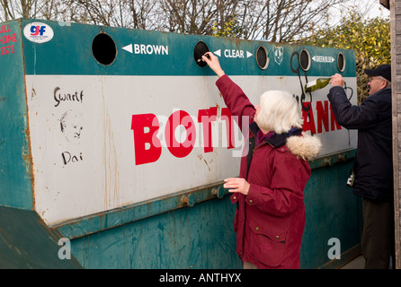 Coppia di mezza età l uomo e la donna il riciclaggio di bottiglie di vetro in una bottiglia di banca, Aberystwyth Wales UK Foto Stock
