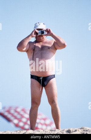 Uomo in piedi sulla spiaggia di scattare una foto Foto Stock