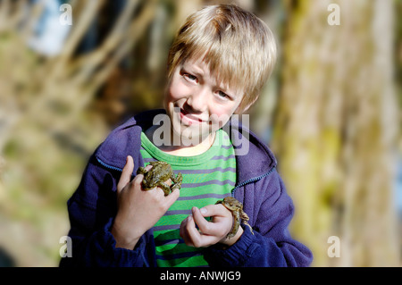 Politica europea comune in materia di toad ( Bufo bufo ) giacente sulla mano di un periodo di nove anni del bambino Foto Stock