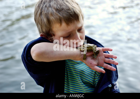 Bambino di sette anni con smooching comune rospo europea ( Bufo bufo ) giacente sul suo braccio Foto Stock