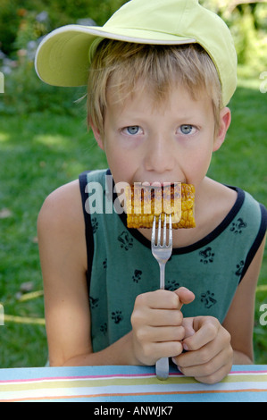 Il ragazzo, undici anni, è mangiare fritto o grigliato del mais Foto Stock