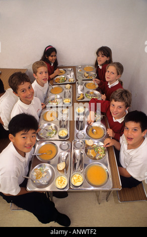 MULTICULTURALE PASTI SCOLASTICI SANI CENE Gruppo di studenti di scuole elementari multietniche che hanno un sano pranzo equilibrato nella mensa scolastica Foto Stock