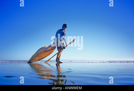 L'uomo tirando i kayak sulla spiaggia, Tofino, Isola di Vancouver, British Columbia, Canada. Foto Stock