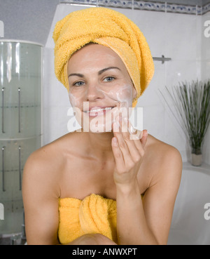 Giovane donna in bagno sfregamento in una crema da giorno Foto Stock