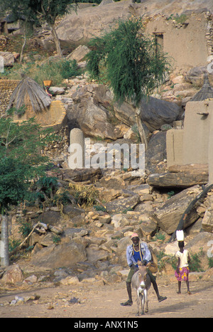 Un uomo a cavallo di un asino e una ragazza che porta un dolore nel villaggio di Ireli Dogon, in Mali, Africa. (MR) Foto Stock