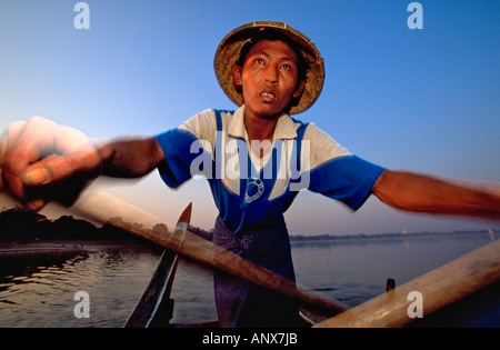 I barcaioli birmani canottaggio la sua imbarcazione sul lago Taungthaman vicino Amarapura U Bein Bridge, Myanmar (Birmania), Asia. Foto Stock