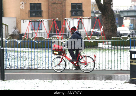 Nero portalettere rdiing rosso in bici sulla neve Foto Stock