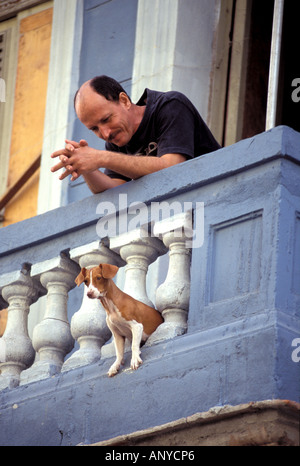 Caraibi Cuba, La Habana. Havana Centrale, uomo sul balcone con il cane Foto Stock