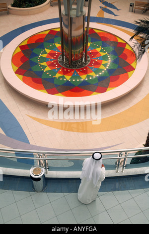 Un uomo musulmano in costume tradizionale guarda verso il basso su una fontana da un balcone, Abu Dhabi, Emirati arabi uniti Foto Stock