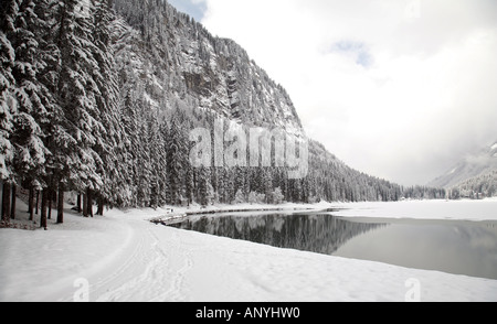 Lac de Montriond, parzialmente ghiacciato in inverno con la neve tutto intorno, coperta di neve abeti, montagne delle Alpi, Francia Foto Stock