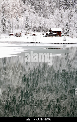 Paesaggi innevati, chalet ed abeti, tutto si riflette nel ghiaccio coperto lago, 'Lac de' Montriond Morzine le Alpi francesi Foto Stock