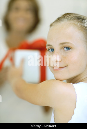 Ragazza con out presente alla donna, sorridente sulla spalla in telecamera Foto Stock