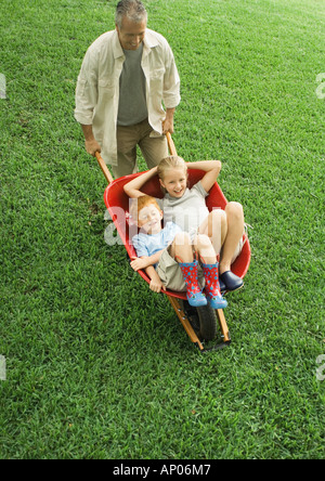 Spingendo il padre di due bambini in carriola Foto Stock