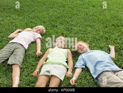 Tre bambini che giace in erba Foto Stock