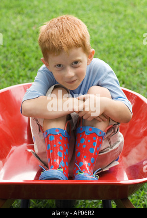 Piccolo Ragazzo seduto in carriola Foto Stock