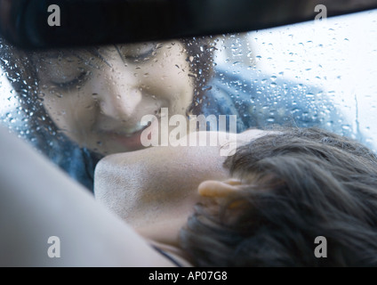 Donna che sta per baciare uomo attraverso il parabrezza Foto Stock