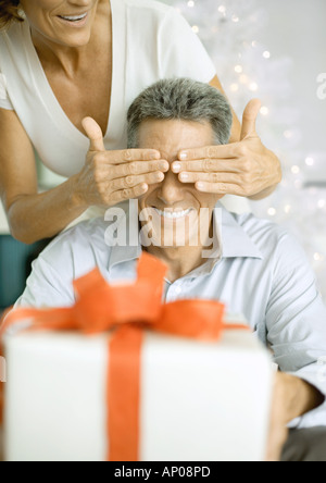 Donna Uomo che copre gli occhi prima di dare a lui un regalo di natale Foto Stock