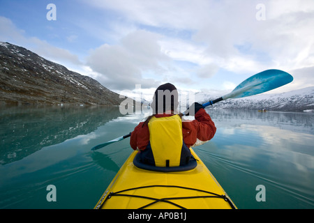 Giovane donna padling un giallo in kayak il lago norvegese del ghiacciaio jostedalsbreen Foto Stock