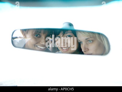 Tre giovani donne, volti riflessi in specchietto retrovisore Foto Stock