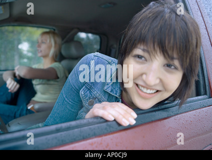 Donna testa di incollaggio al di fuori della finestra di auto Foto Stock