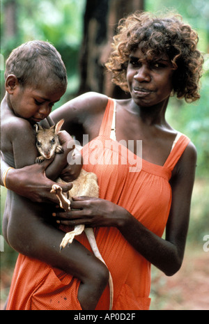 Presto la donna con il suo bambino coccole pet baby kangaroo la cui madre uccisi per cibo di Arnhem Land NT Australia Foto Stock