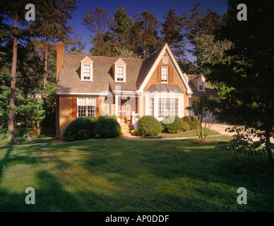 Mattone due piani di casa con persiane rosse un grande prato e un camino Foto Stock
