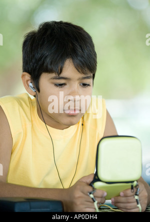 Preteen ragazzo indossa gli auricolari e custodia di contenimento Foto Stock