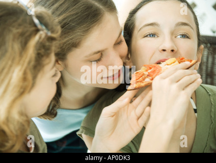 Tre ragazze preteen, alimentando amico pizza Foto Stock