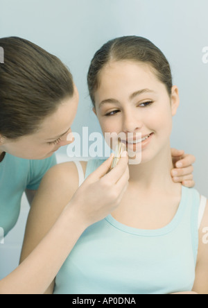 Ragazza adolescente mettendo il rossetto su un amico Foto Stock