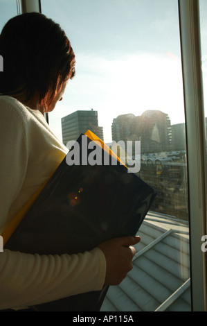 Business donna guardando fuori della finestra di ufficio azienda file vista posteriore Foto Stock