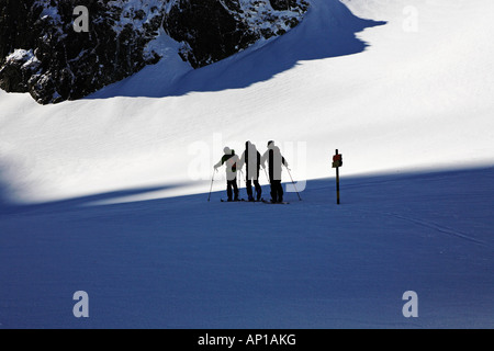 Tre persone in un tour di sci, in ordine ascendente di una montagna, passando un segno posto. Sci i turisti sono sulla loro strada fino alla sommità del Maljov Foto Stock
