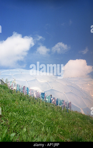 Colorati bandiere di preghiera visualizzato nella parte anteriore di un biodome all'Eden Project, Cornwall Foto Stock