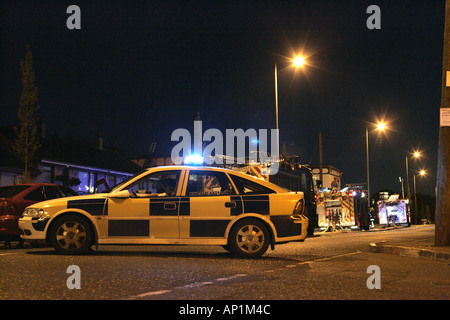 La squadra di polizia auto e i veicoli antincendio partecipare al fuoco a bracci Cloughfern lealisti durante il feudo di notte Foto Stock