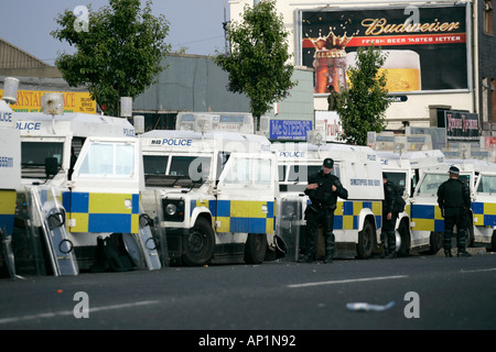 Linea di PSNI landrovers e ufficiali a Crumlin road presso negozi di ardoyne belfast xii Luglio Foto Stock