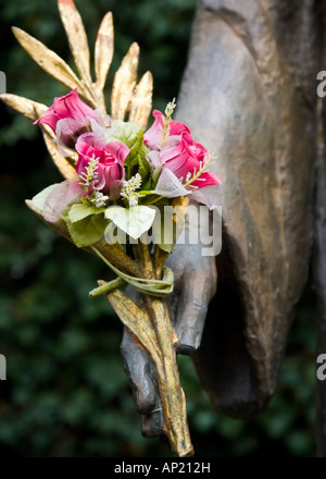 La mano della Vergine Maria tenendo un piccolo bouquet di rose rosse nella città di Triora, Nord Italia Foto Stock