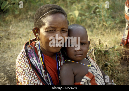 Donna Maasai holding e consolante il suo bambino vicino alla Riserva Nazionale di Masai Mara Kenya Africa orientale Foto Stock