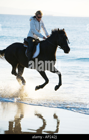 Giovane donna al galoppo sul suo cavallo sulle spiagge della costa de la luz Tarifa Cadiz Spagna Foto Stock