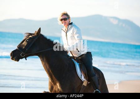 Giovane donna a cavallo sulla spiaggia Foto Stock