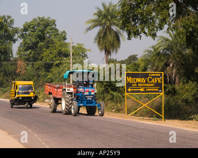 A tre ruote Auto Rickshaw taxi locale e il trattore e il rimorchio passando Midway Cafe segno sulla strada rurale vicino Pashwara India Foto Stock