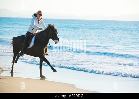 Giovane donna al galoppo sul suo cavallo sulle spiagge della costa de la luz Tarifa Cadiz Spagna Foto Stock