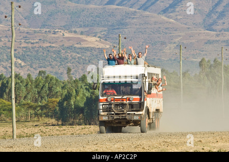 Un overland carrello a velocità su una strada sterrata con i passeggeri sventolare dal tetto sedili e windows del carrello. Foto Stock