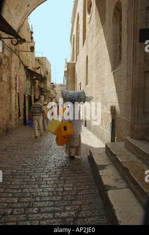 Una donna Palestinese porta un sacco sulla sua testa come lei cammina giù per la strada per la città vecchia di Gerusalemme Israele Foto Stock