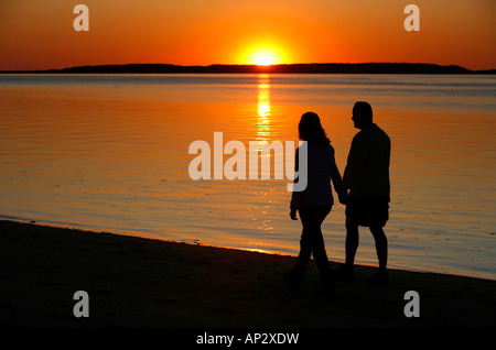 Giovane camminando lungo la spiaggia al tramonto, Wellfleet Harbour, Cape Cod, Massachusetts, STATI UNITI D'AMERICA Foto Stock